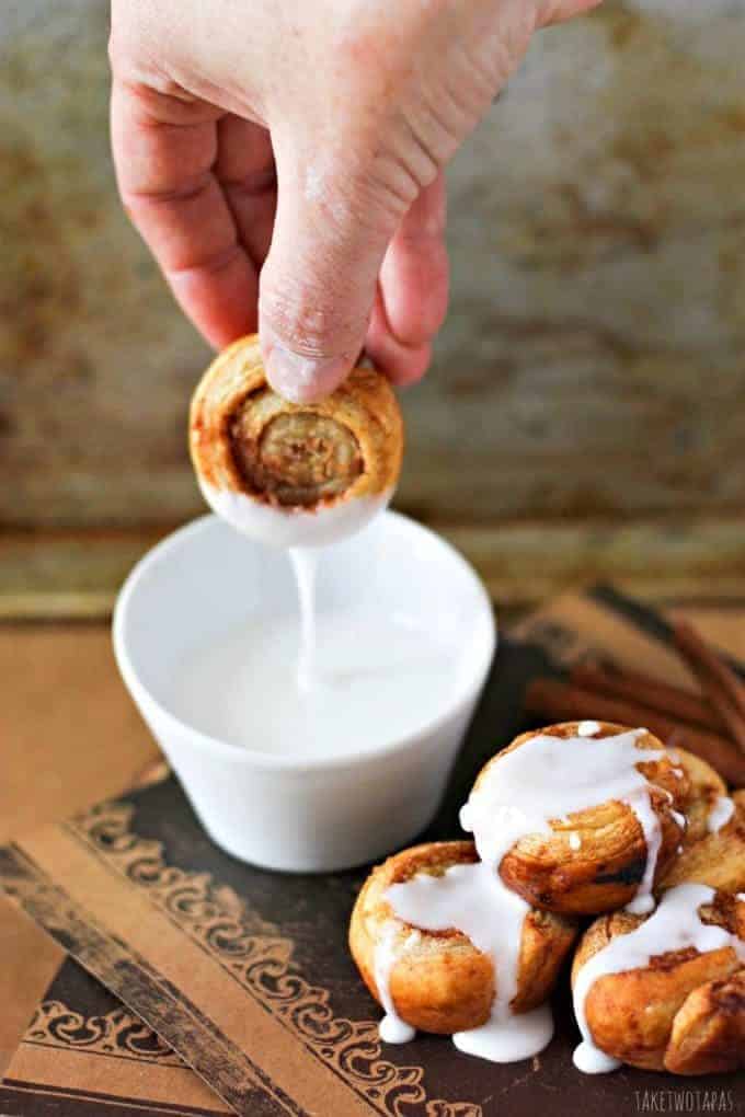 These mini cinnamon roll bites are quickly made with the help of puff pastry. Sprinkled with brown sugar and baked until golden brown, they are crispy on the outside and flaky on the inside. Top them off with vanilla glaze for the perfect bite! Mini Puff Pastry Cinnamon Rolls Recipe | Take Two Tapas