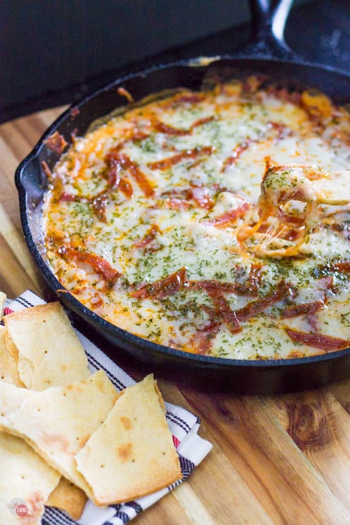 Craving pizza but want something new? Check out this extra cheesy pepperoni pizza dip with thin crust chips for dipping all the cheesy goodness! Extra Cheesy Pepperoni Pizza Skillet Dip with think crust crackers Recipe | Take Two Tapas