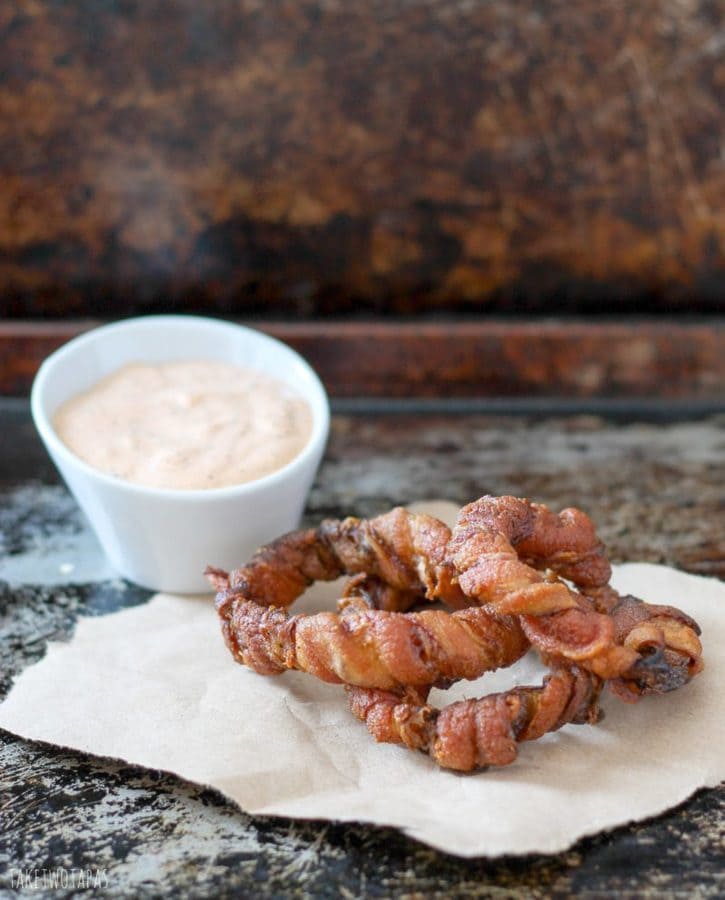 These bacon wrapped onion rings are the perfect appetizers for those who are gluten-free! The crispy bacon is perfect wrapped around the sweet, tender onion rings. Dipped in chipotle dipping sauce, these are a great party food! Bacon Wrapped Onion Rings Recipe | Guest post from Take two Tapas