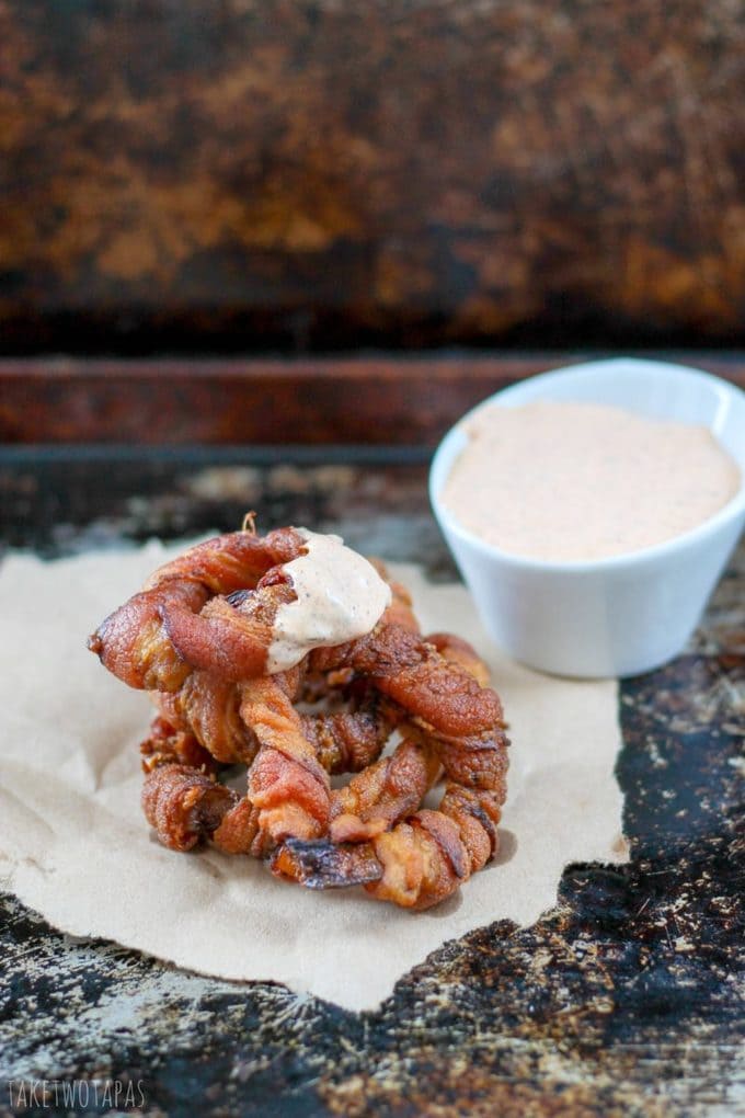 These bacon wrapped onion rings are the perfect appetizers for those who are gluten-free! The crispy bacon is perfect wrapped around the sweet, tender onion rings. Dipped in chipotle dipping sauce, these are a great party food! Bacon Wrapped Onion Rings Recipe | Guest post from Take two Tapas