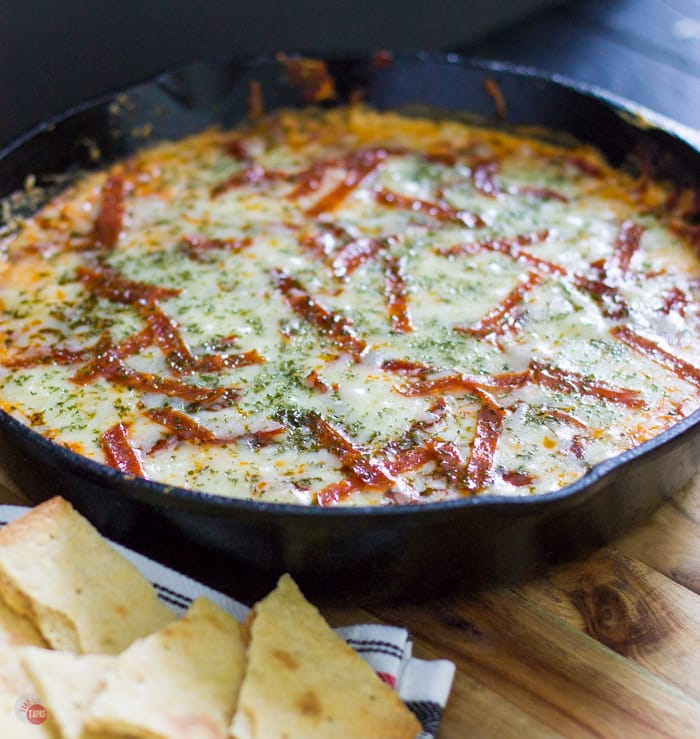 Craving pizza but want something new? Check out this extra cheesy pepperoni pizza dip with thin crust chips for dipping all the cheesy goodness! Extra Cheesy Pepperoni Pizza Skillet Dip with think crust crackers Recipe | Take Two Tapas