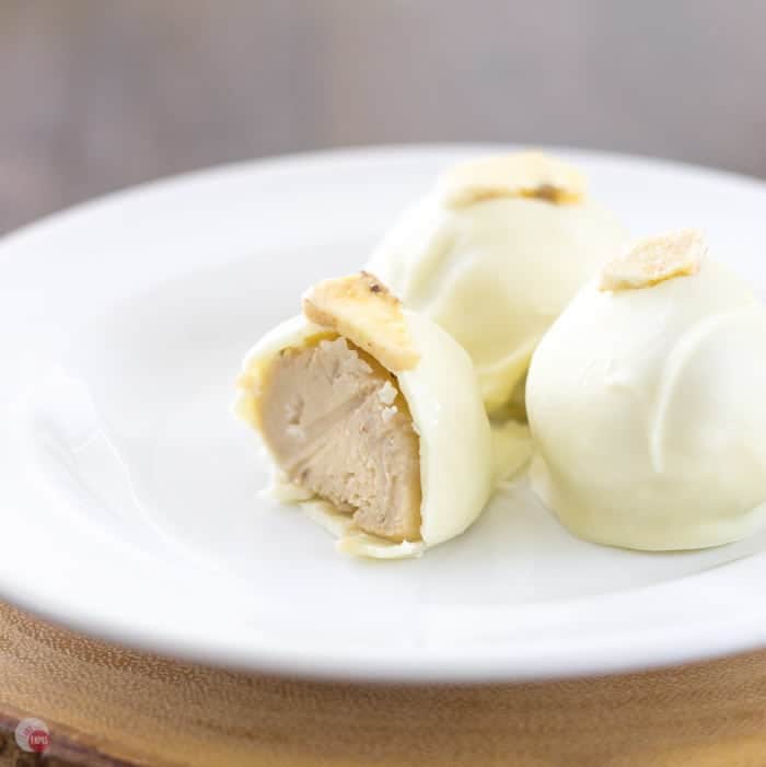 Close up of Creamy Banana Pudding Truffles on a white plate and one has a bite taken out of it.