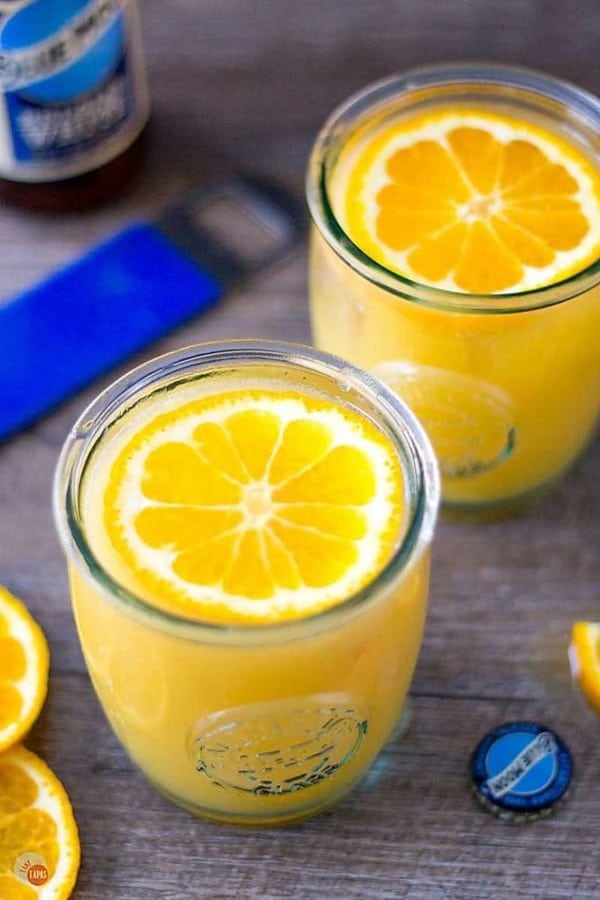 Two Satsuma Orange Shandy cocktails with an orange slice floating on top.