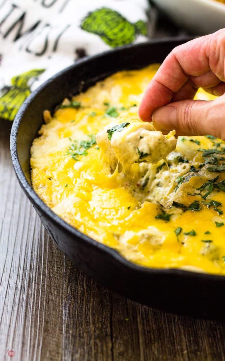 hand dipping a chip in to the chile relleno skillet dip