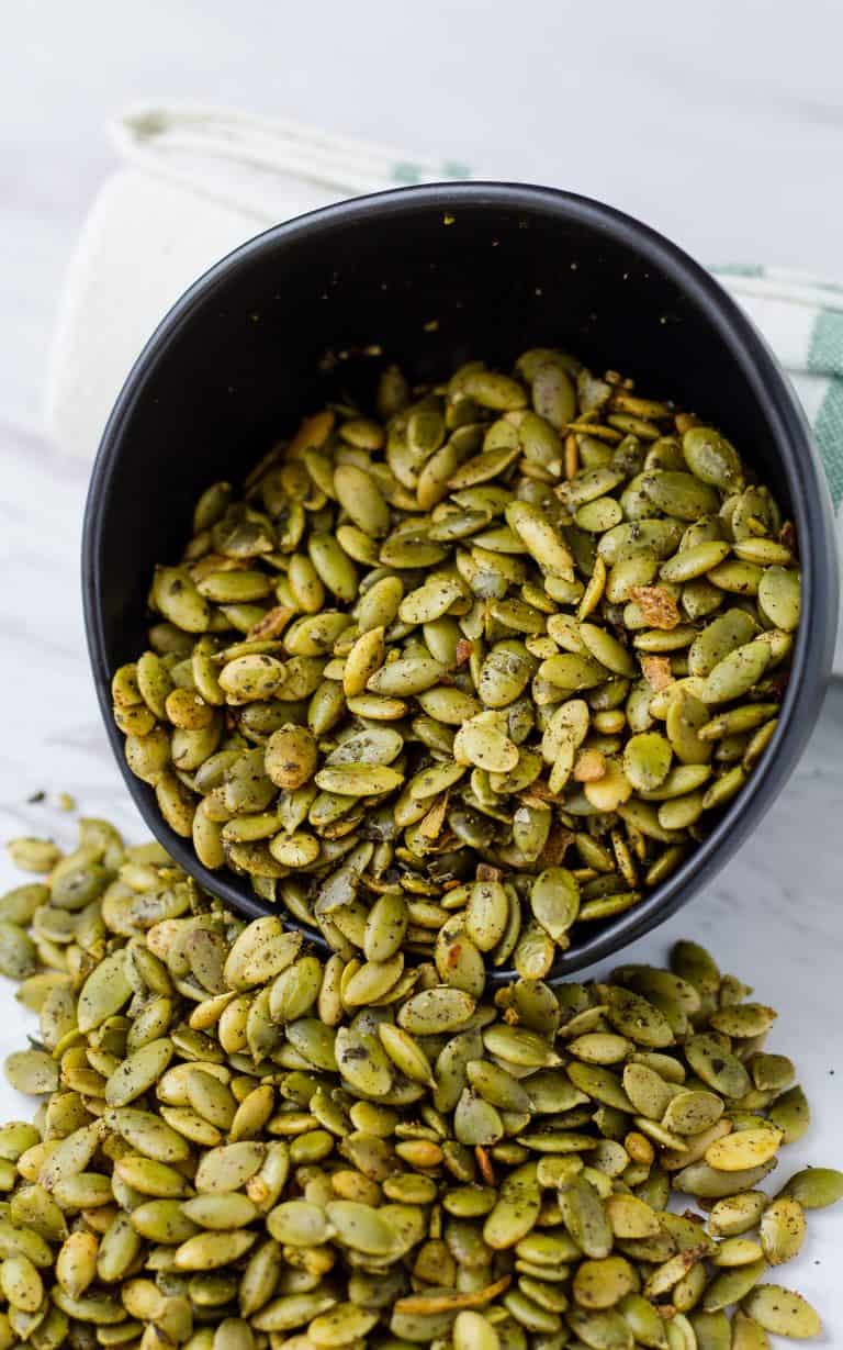 Crunchy Southwest Pepitas spilling out of a bowl on to a table