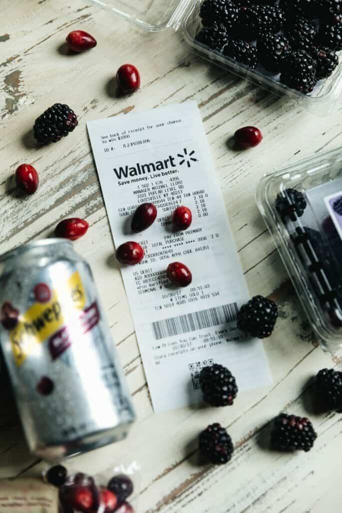 a can of schweppes, cranberries and blackberries on a white washed surface.