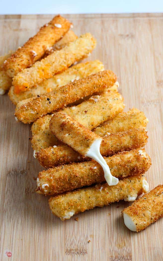 stack of mozzarella sticks on a wood cutting board