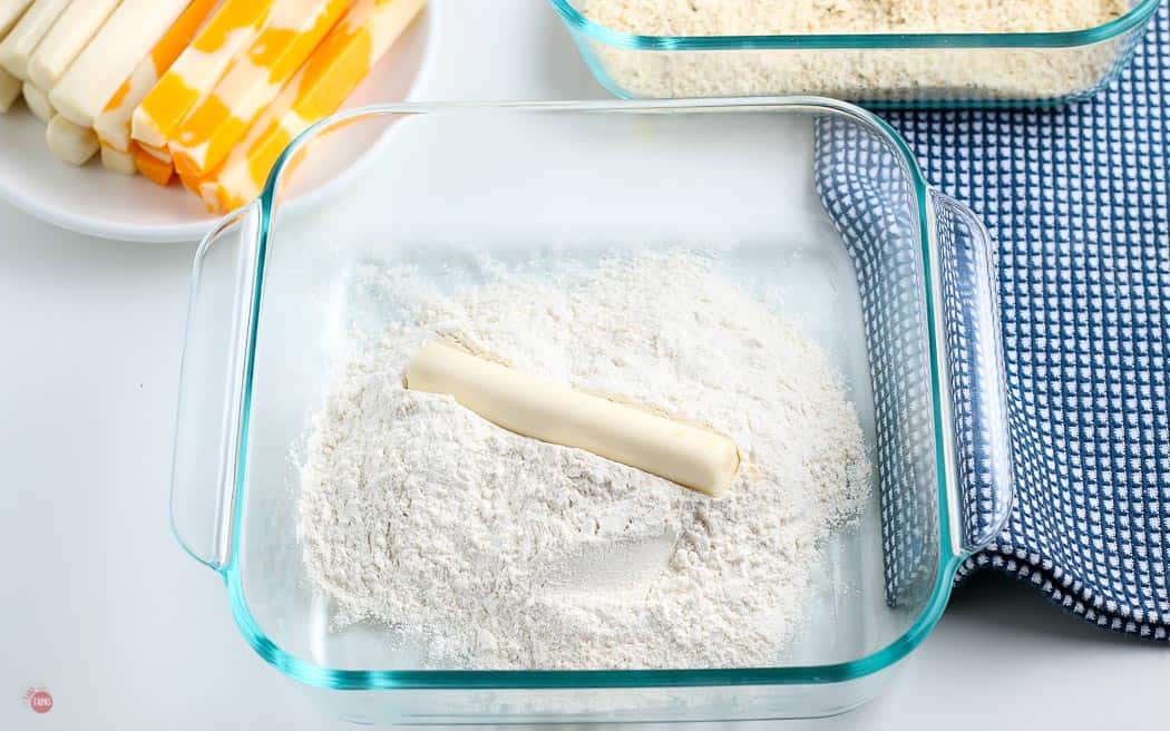 cheese stick in a glass bowl of flour