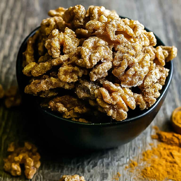 closeup of sugared walnuts in a black bowl