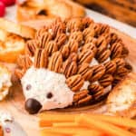 hedgehog cheese ball on a wood board with carrot sticks