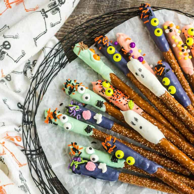 square picture of spooky chocolate dipped pretzels on parchment paper