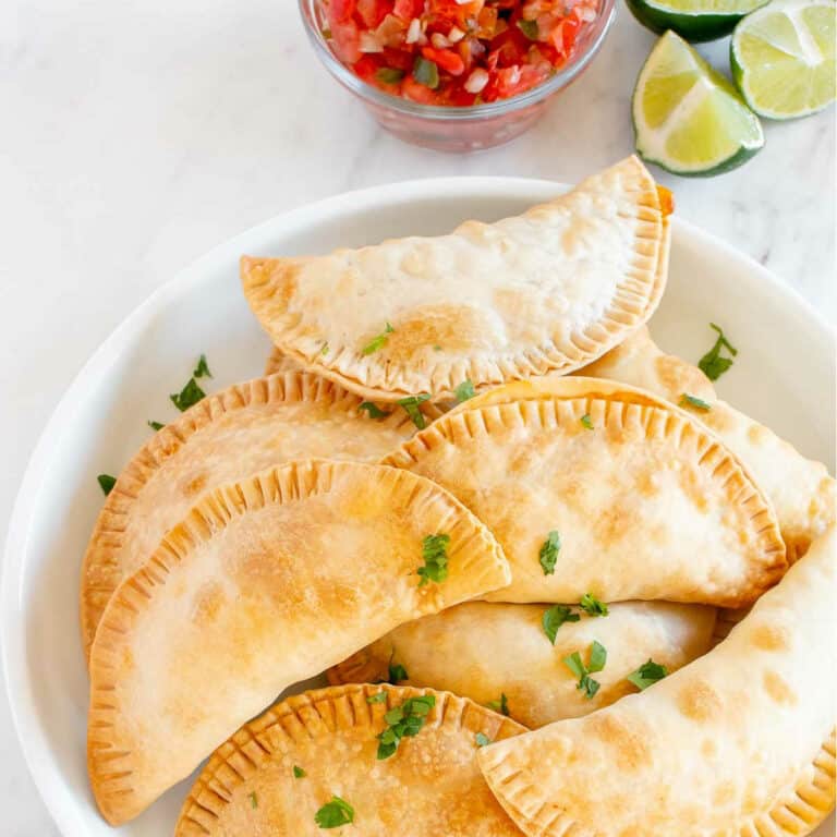 plate of corn empanadas with limes and salsa