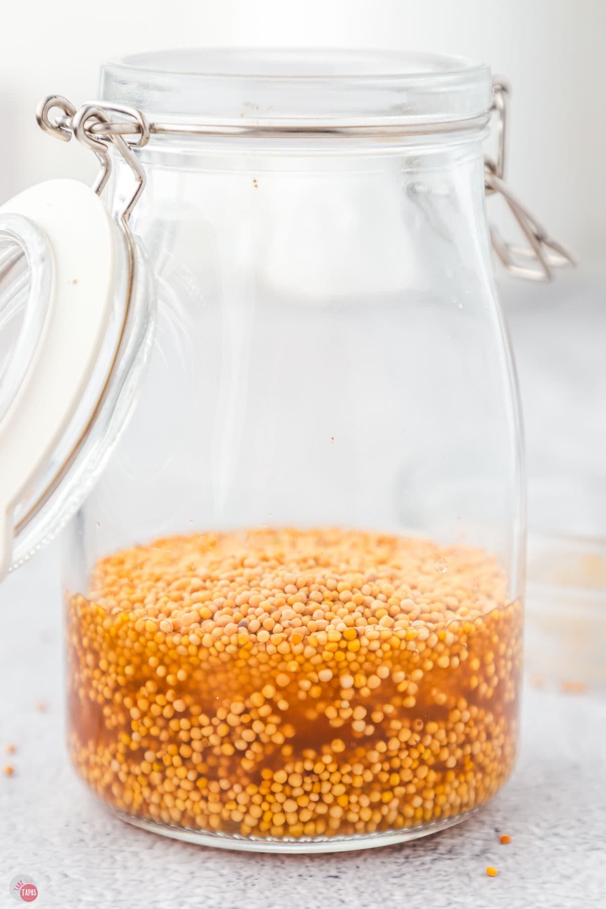 jar of mustard seeds and vinegar sitting on a counter