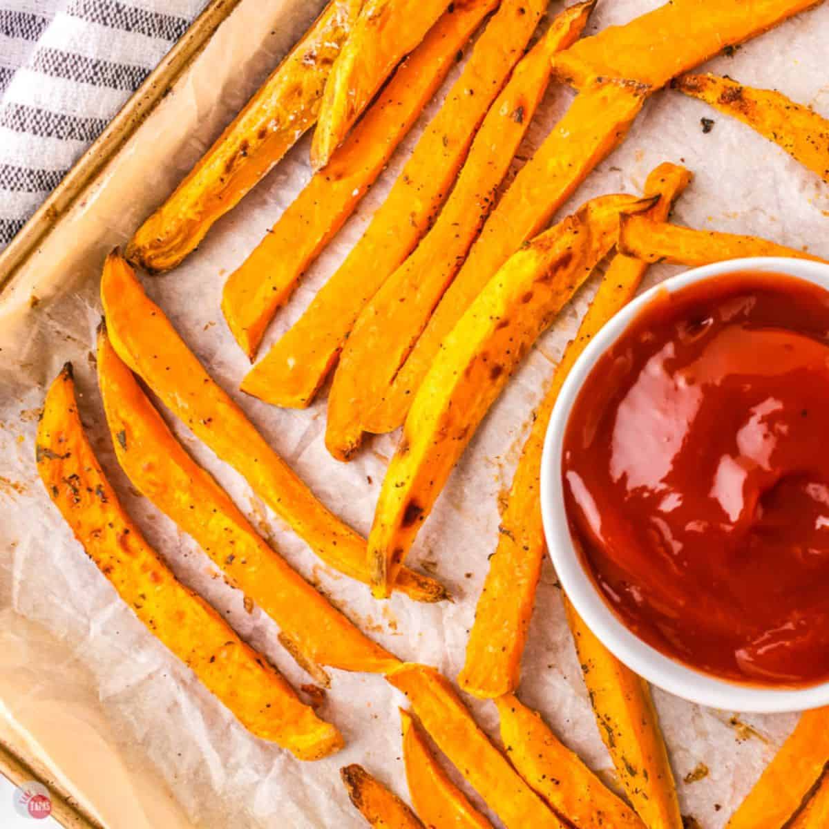 sweet potato fries on a baking sheet with bowl of ketchup