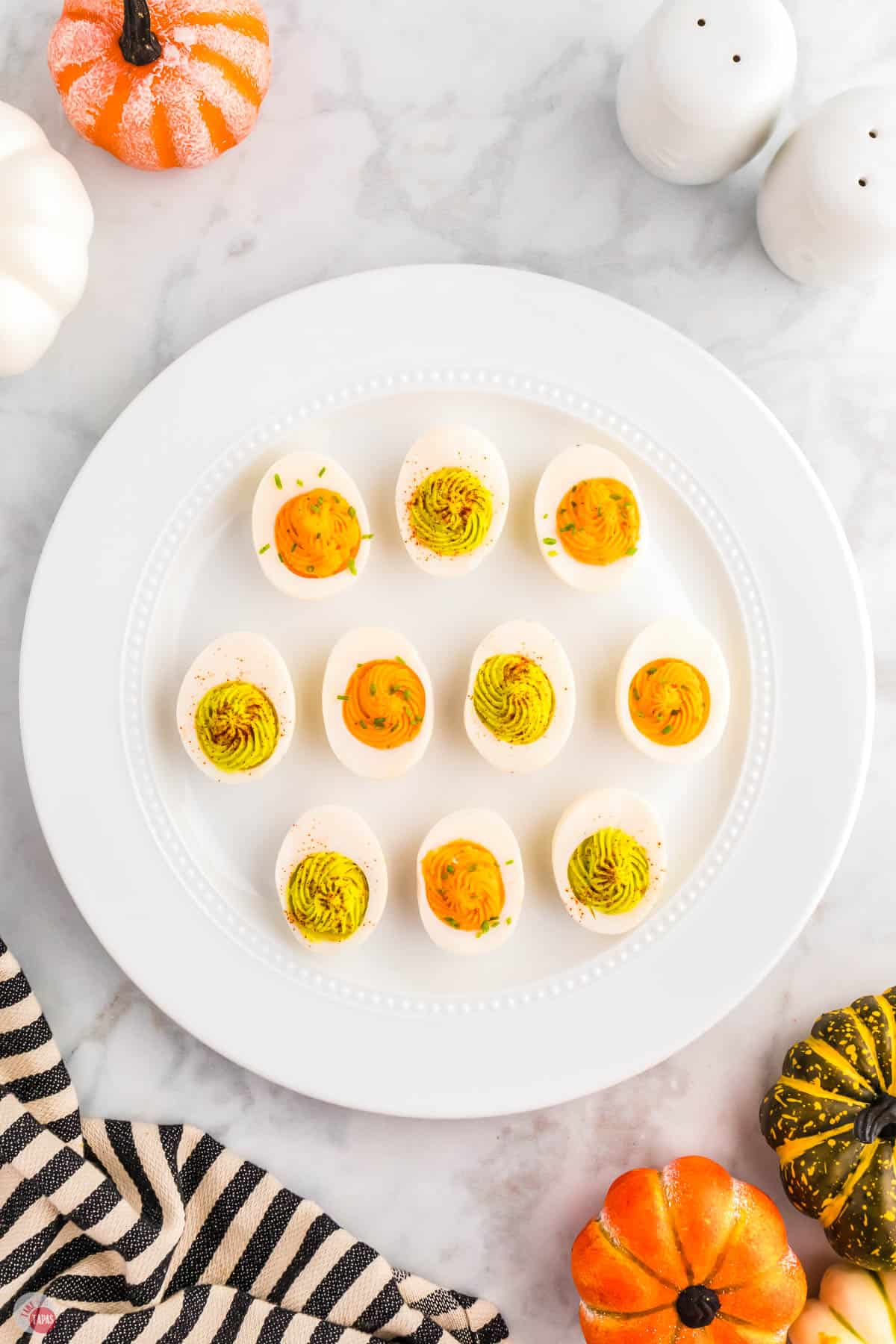 halloween eggs on a white plate with mini pumpkins