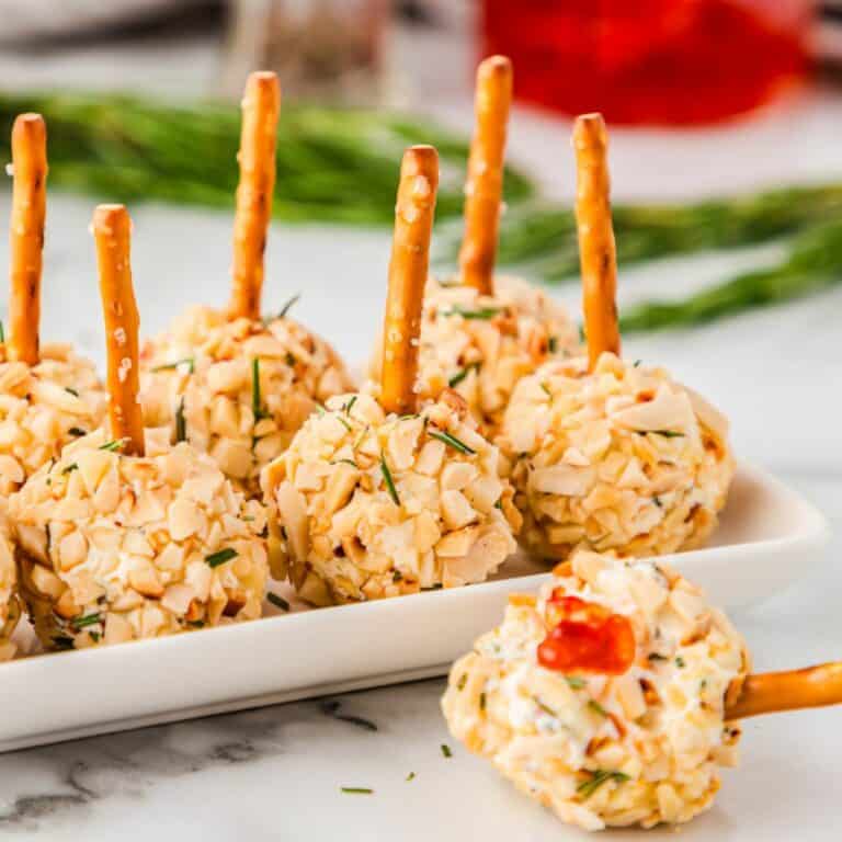 mini cheese balls on a tray with pretzel stick handles