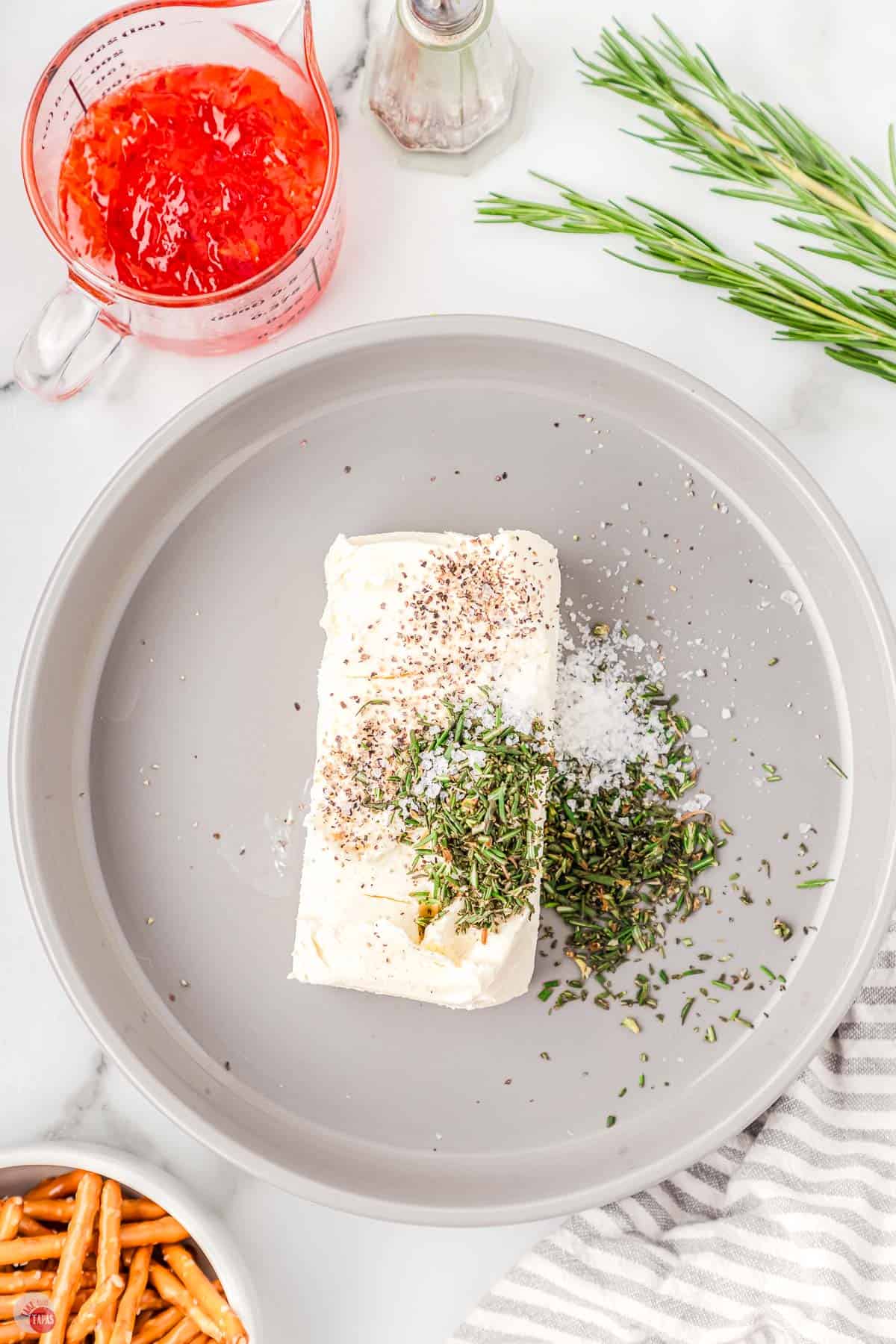 block of cream cheese on a plate with herbs on top