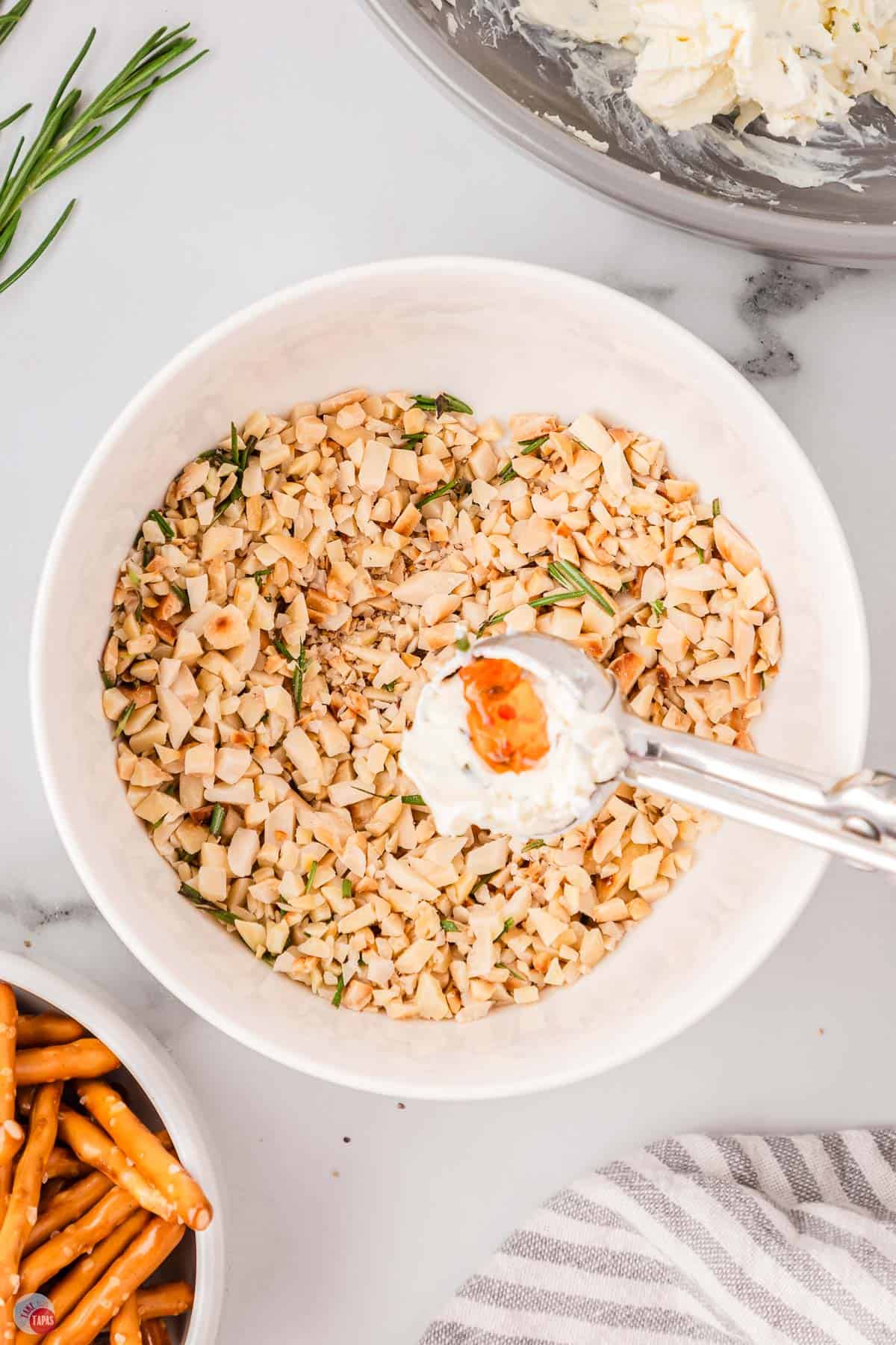 scoop of cream cheese over a bowl of chopped nuts