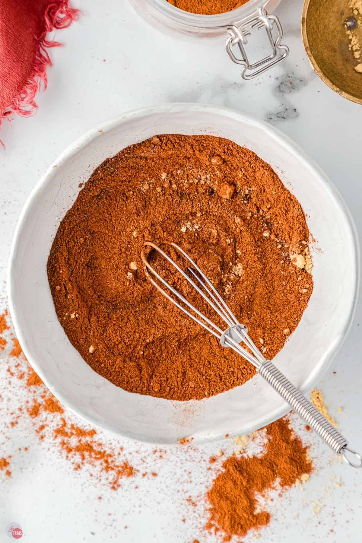 whisk combining spices in a white bowl