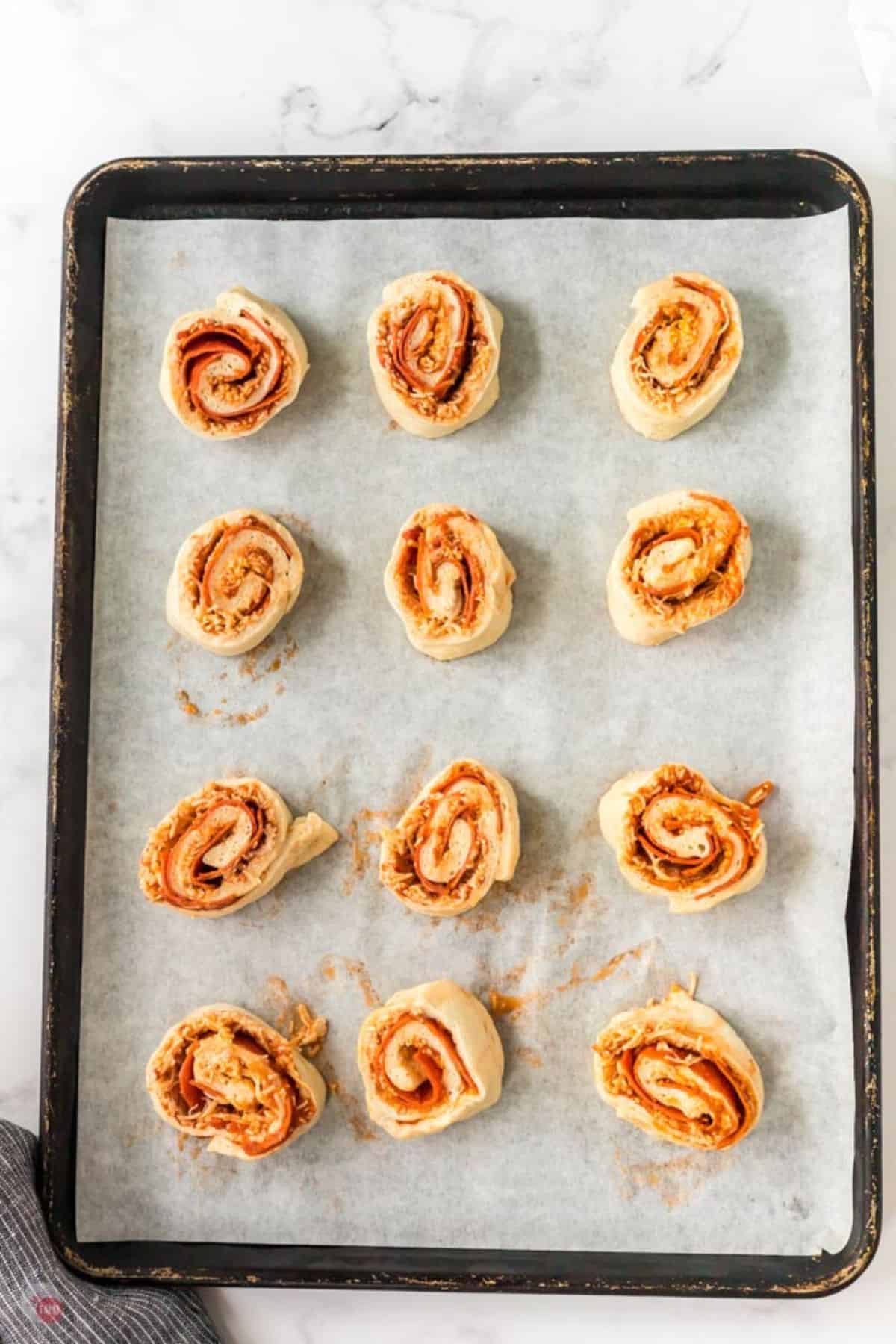 pizza pinwheels unbaked on a sheet