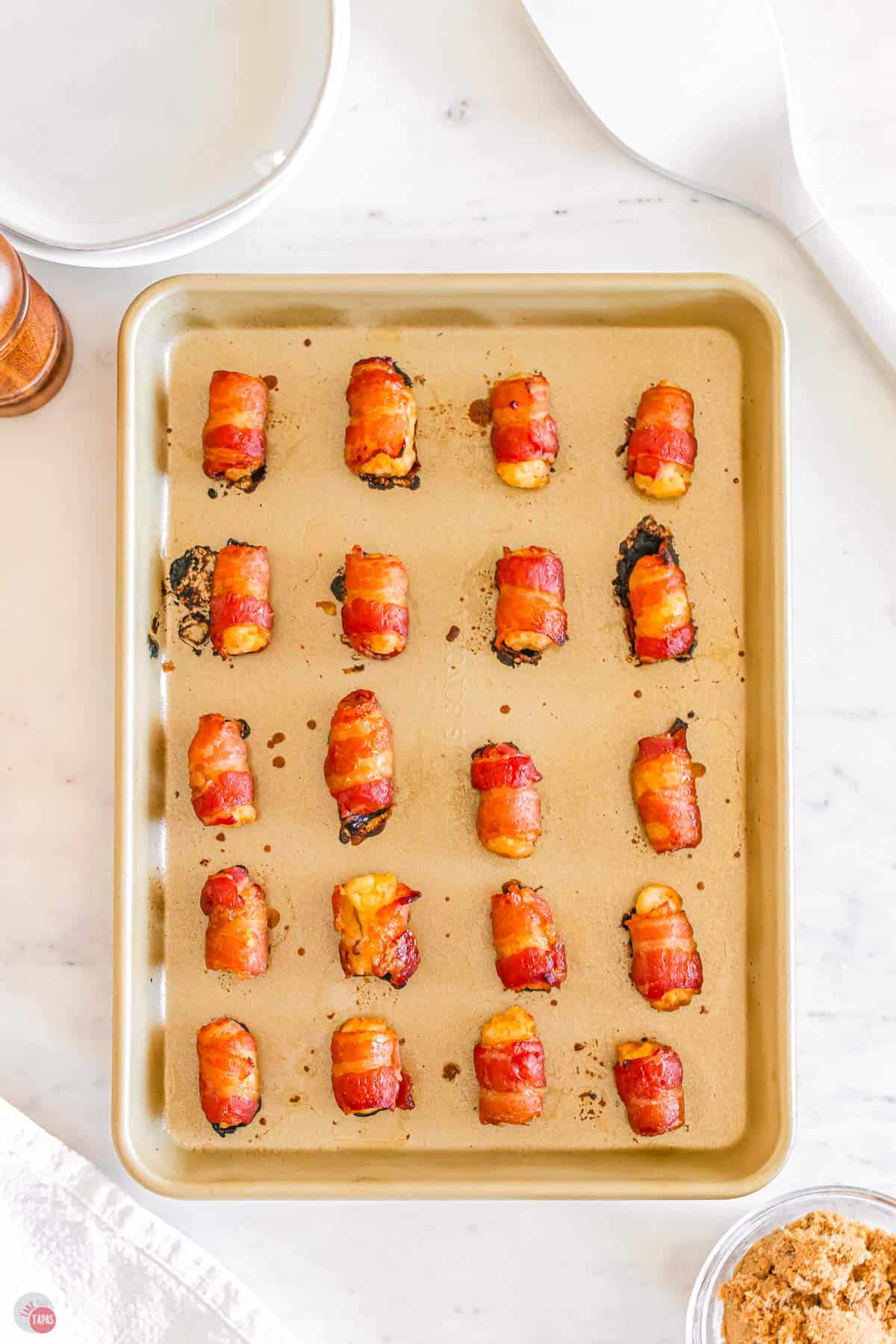 baked bacon wrapped tater tots on a baking sheet