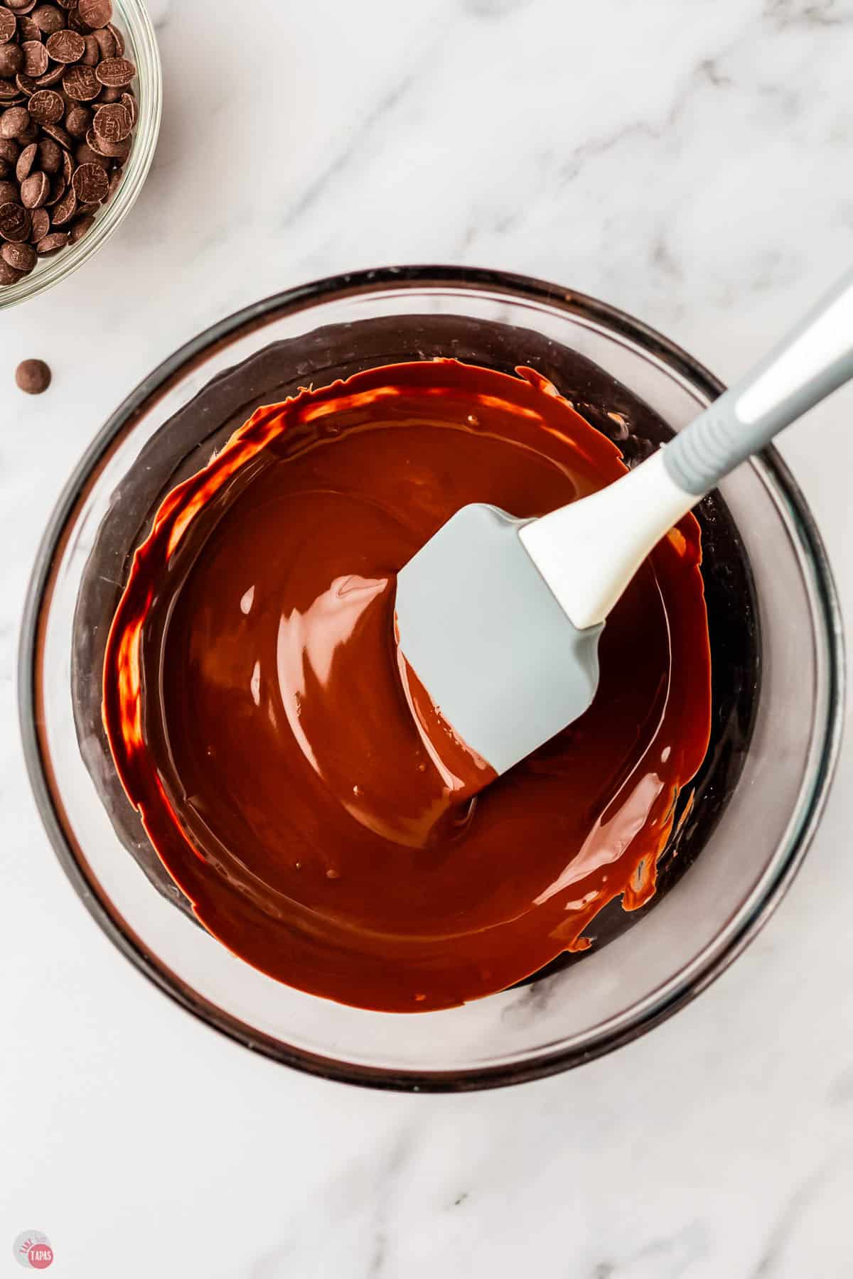 melted chocolate in a microwave safe bowl with a spatula