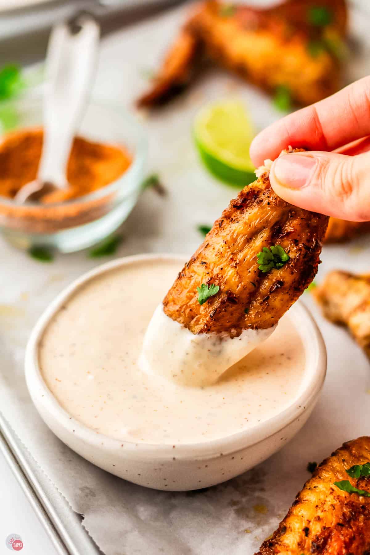 jerk chicken wings being dipped in a bowl