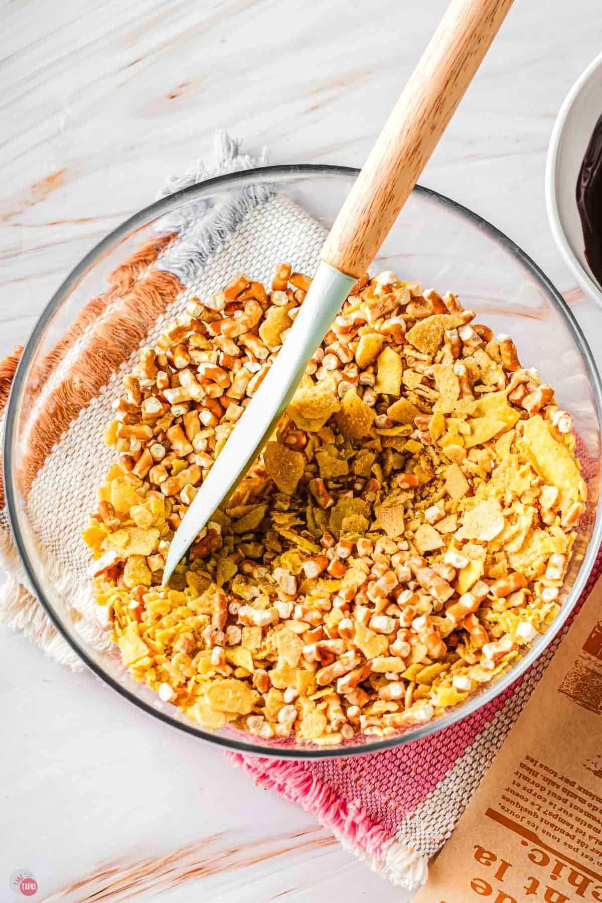 bowl of crushed chips and pretzels with a spatula