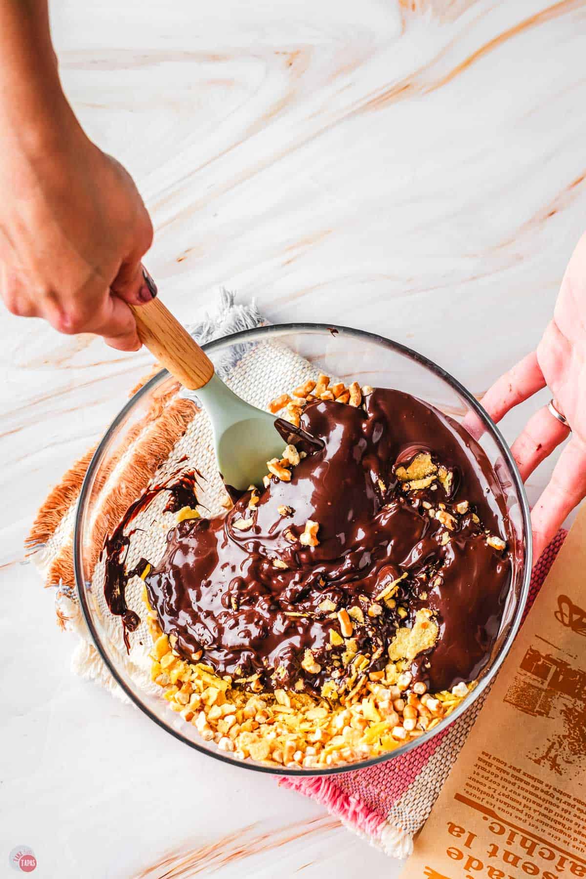 hand holding a spatula, stirring chocolate and crushed potato chips